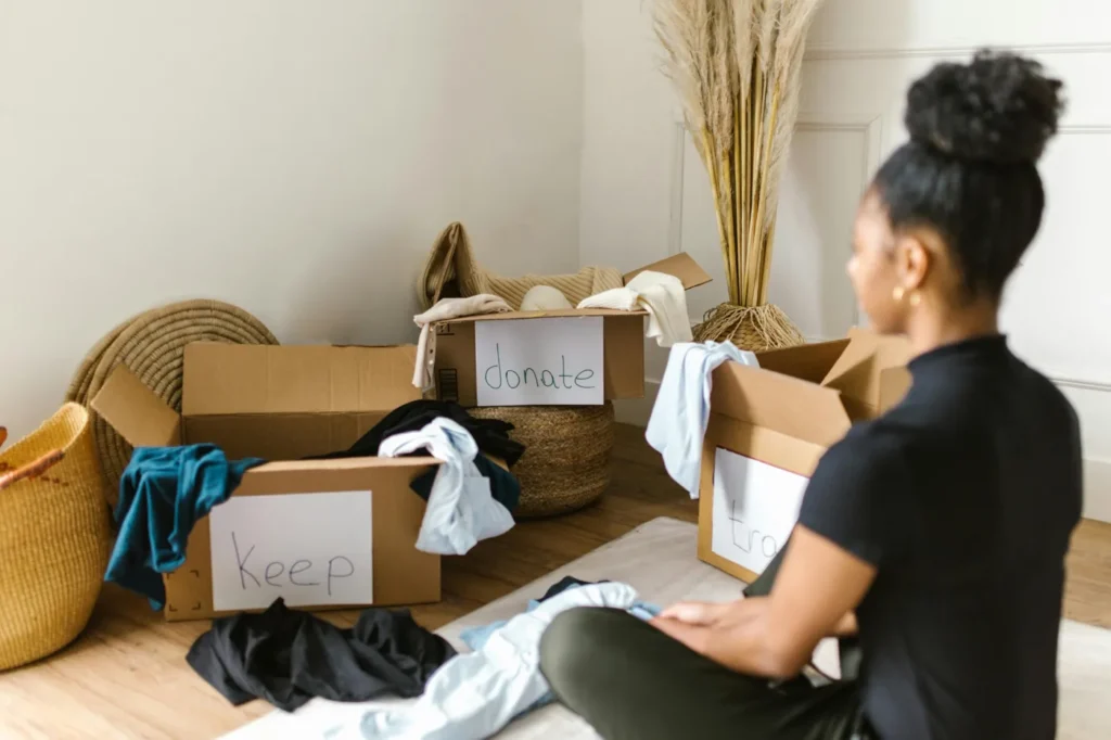Woman organizing clothes into keep and donate piles during home decluttering process